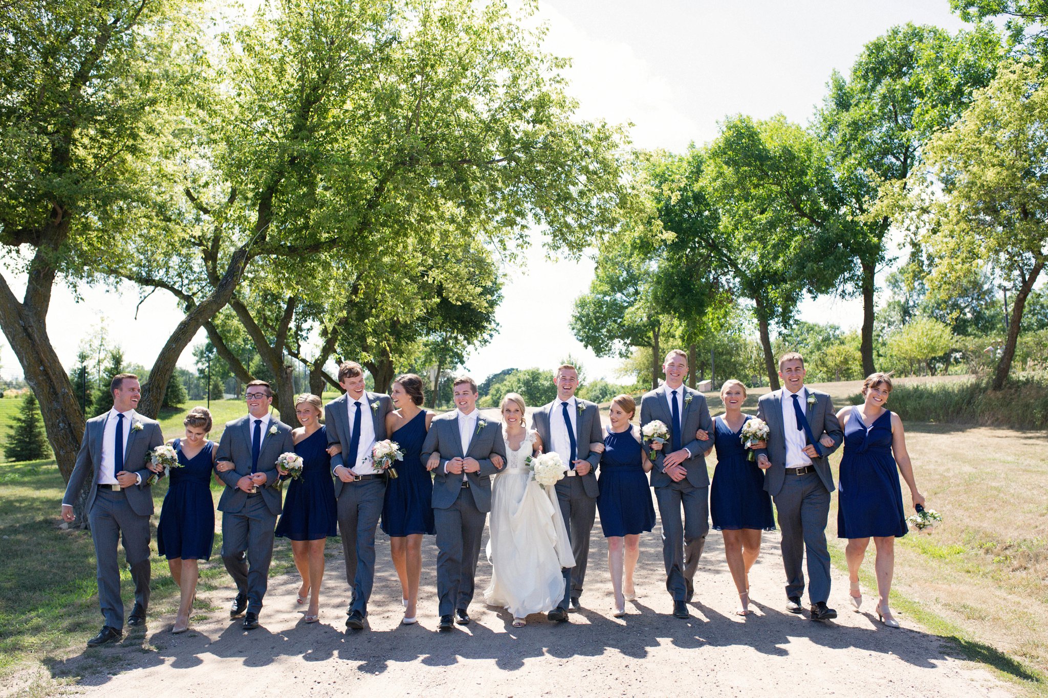 Sioux Falls Wedding Photos | Destination Photographer | Felicia The Photographer | Mary Jo Wegner Arboretum | Bridal Party | Navy one shoulder dresses | Walking | Candid