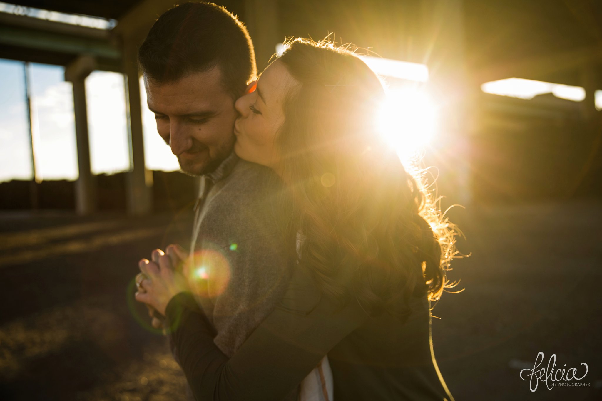 engagement photos | engagement photography | Kansas City | West Bottoms | images by feliciathephotographer.com | urban setting | industrial background | sun flare | romantic pose | kiss on cheek | holding hands | bridge background 