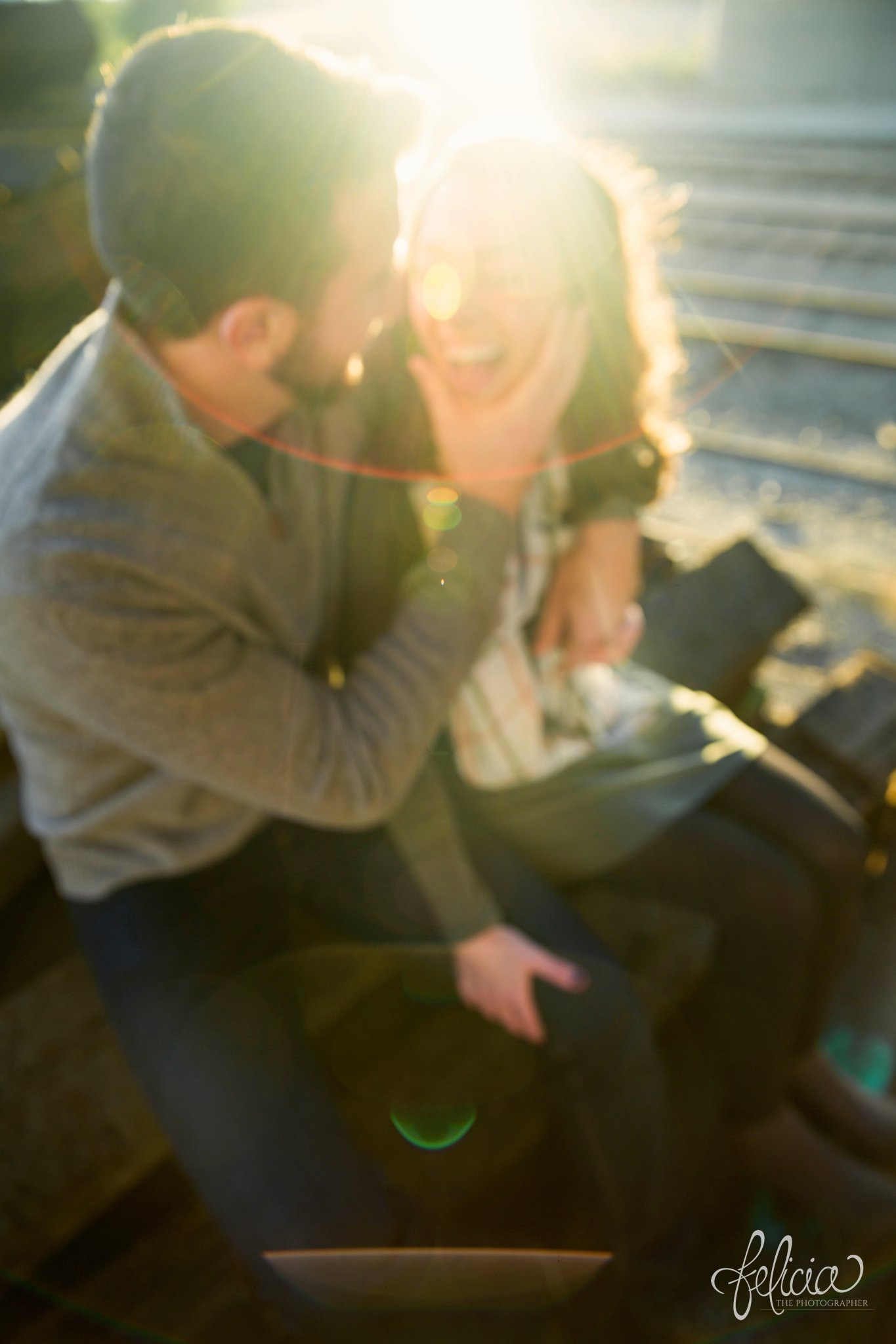 engagement photos | engagement photography | Kansas City | West Bottoms | images by feliciathephotographer.com | urban setting | industrial background | engagement shoot | candid | hand on cheek | sun flare | laughing 