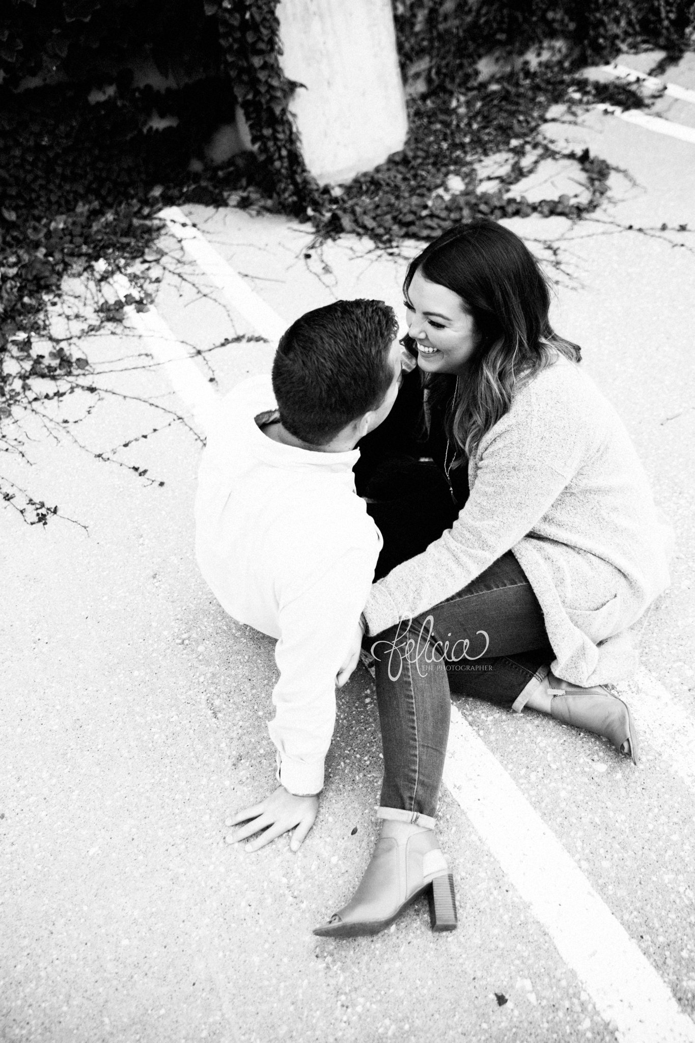 black and white | engagement photos | engagement photography | Kansas City | images by feliciathephotographer.com | architectural backgrounds | happy couple | laughter | candid | sitting | smiles | aerial view | concrete sidewalk 
