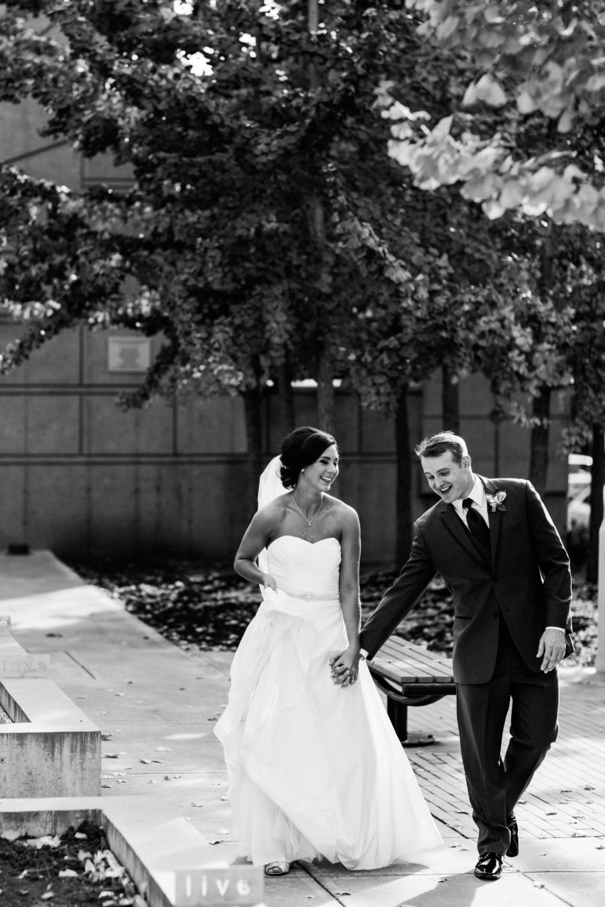 black and white | wedding | wedding photos | wedding photography | images by feliciathephotographer.com | Country Club Plaza | Kansas City | Unity Temple | Cancer Survivor Park | bride and groom portraits | candid | walking through park | hand holding | laughing bride | laughing groom | silly poses 