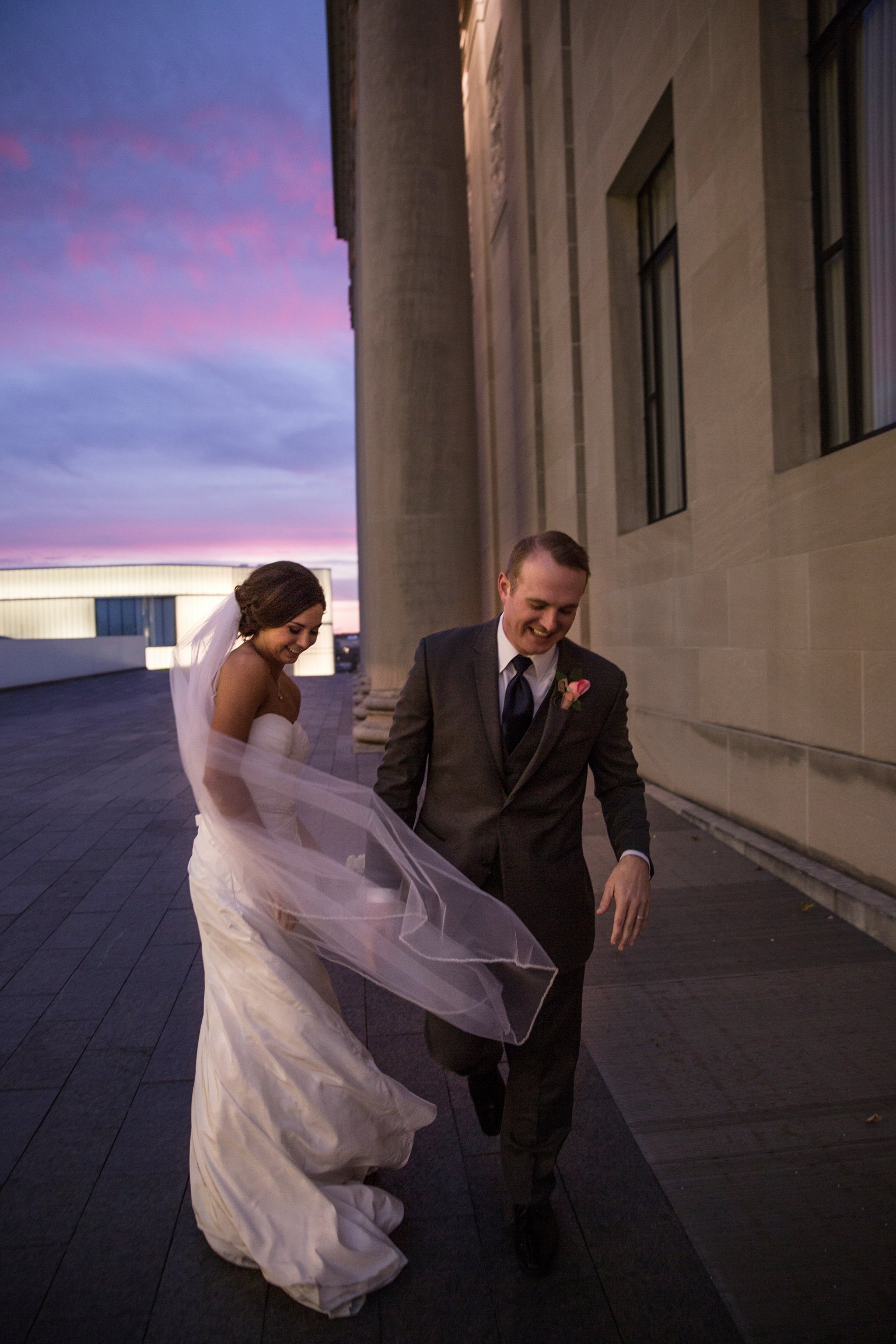 wedding | wedding photos | wedding photography | images by feliciathephotographer.com | Country Club Plaza | Kansas City | Unity Temple | Nelson Atkins Museum of Art | sunset photography | sunset portraits | bride and groom portraits | purple sky | laughing | candid | billowing veil 
