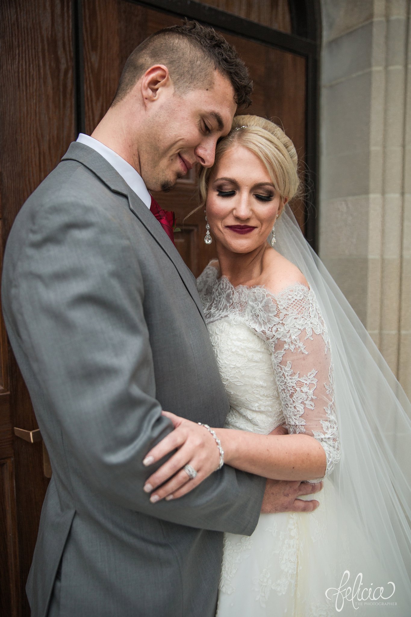 wedding | wedding photography | wedding photos | Kansas City | St. Patrick's Catholic Church | Hawthorne House | images by feliciathephotographer.com | crimson wedding | Christmas Wedding | winter portraits | dramatic veil | lace sleeves | lace wedding dress | Paula Varsalona | bride and groom | church background | stone background | romantic pose | stone arch | wooden door 