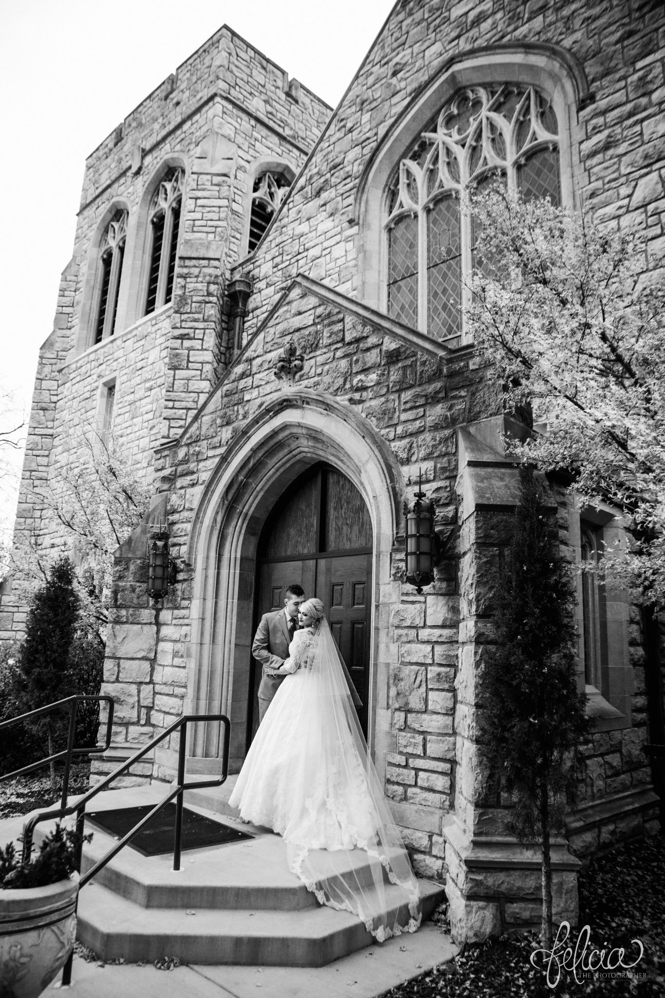 black and white | wedding | wedding photography | wedding photos | Kansas City | St. Patrick's Catholic Church | Hawthorne House | images by feliciathephotographer.com | crimson wedding | Christmas Wedding | winter portraits | dramatic veil | lace sleeves | lace wedding dress | Paula Varsalona | bride and groom | embrace | church doors 