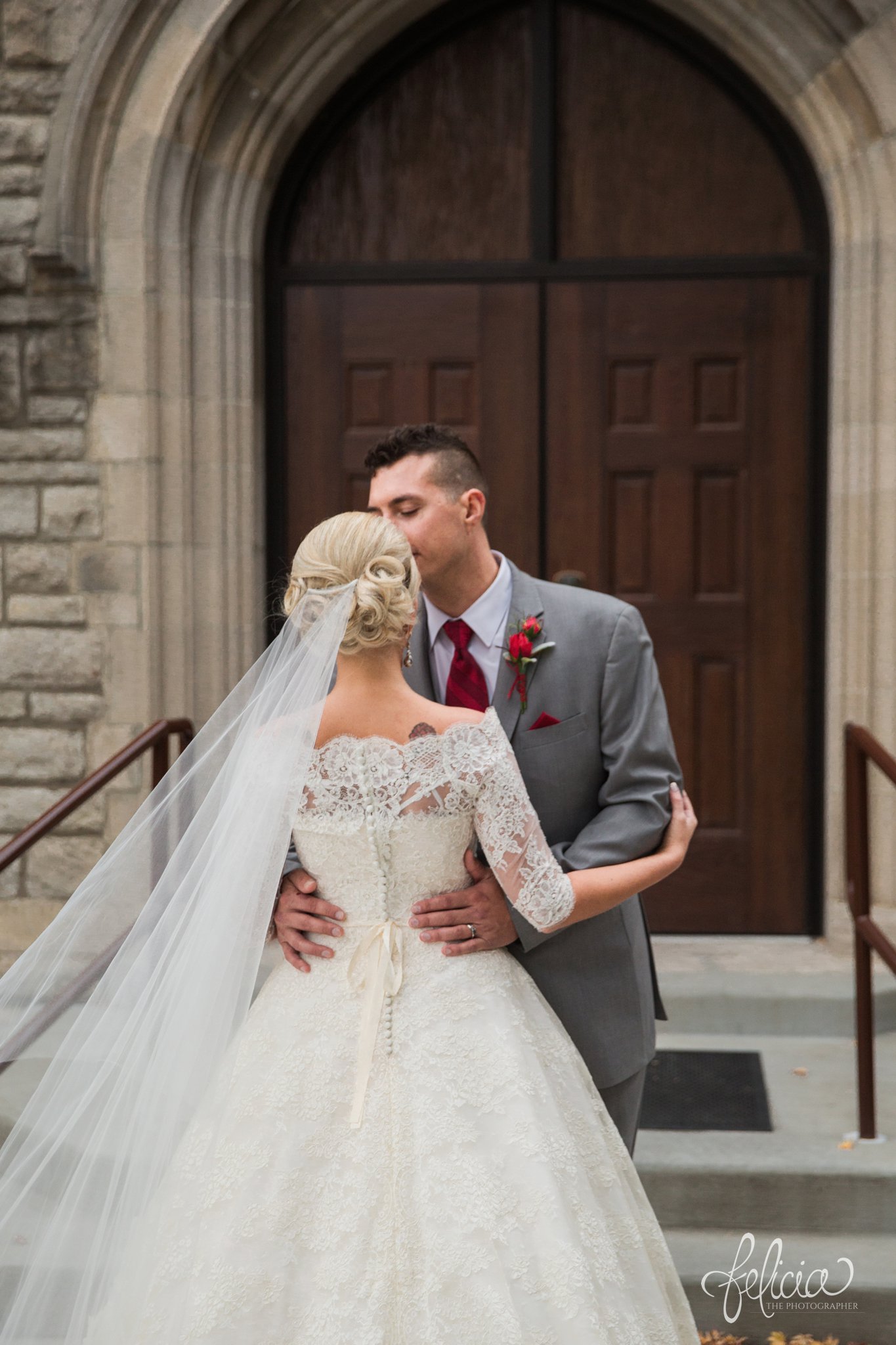 wedding | wedding photography | wedding photos | Kansas City | St. Patrick's Catholic Church | Hawthorne House | images by feliciathephotographer.com | crimson wedding | Christmas Wedding | winter portraits | dramatic veil | lace sleeves | lace wedding dress | Paula Varsalona | bride and groom | embrace | church doors | back to camera | forehead kiss 