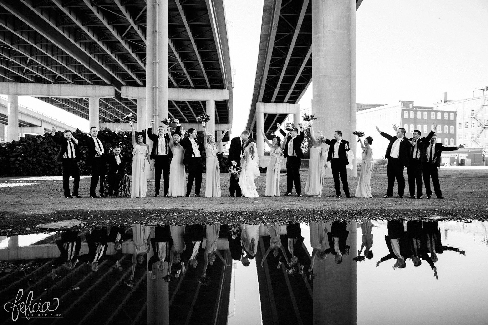 black and white | wedding | wedding photos | industrial | Rumely Event Space | wedding photography | images by feliciathephotographer.com | West Bottoms | industrial background | bridal party portraits | long bridesmaid dresses | beige | champagne | dramatic background | Bella Bridesmaids| reflection | candid | raised hands 
