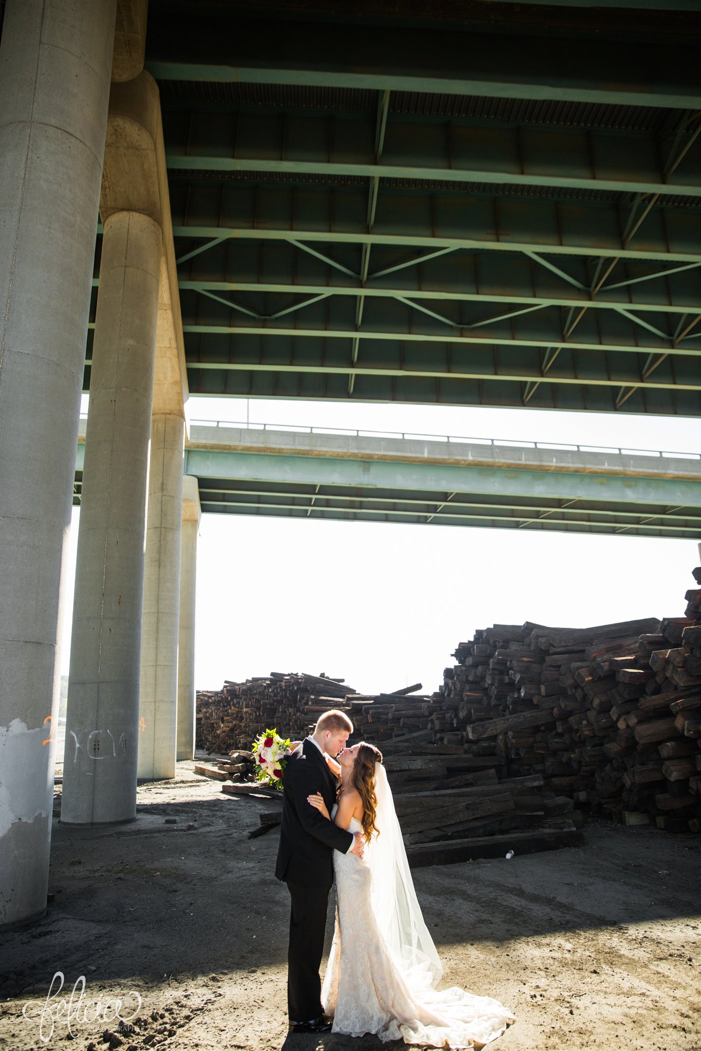 wedding | wedding photos | industrial | Rumely Event Space | wedding photography | images by feliciathephotographer.com | West Bottoms | industrial background | bride and groom portraits | kissing | Maggie Sottero | overpass 
