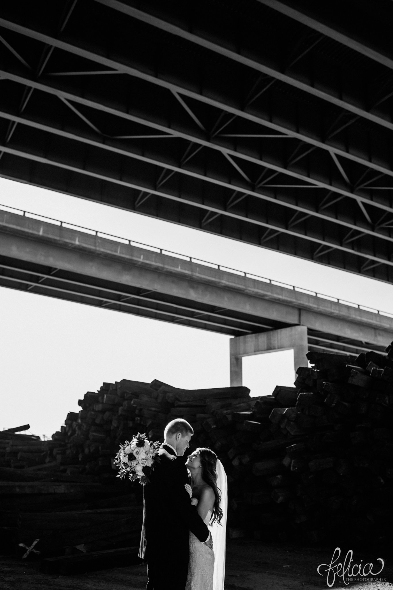 black and white | wedding | wedding photos | industrial | Rumely Event Space | wedding photography | images by feliciathephotographer.com | West Bottoms | industrial background | bride and groom portraits | forehead kiss | romantic pose | dramatic | highway overpass 
