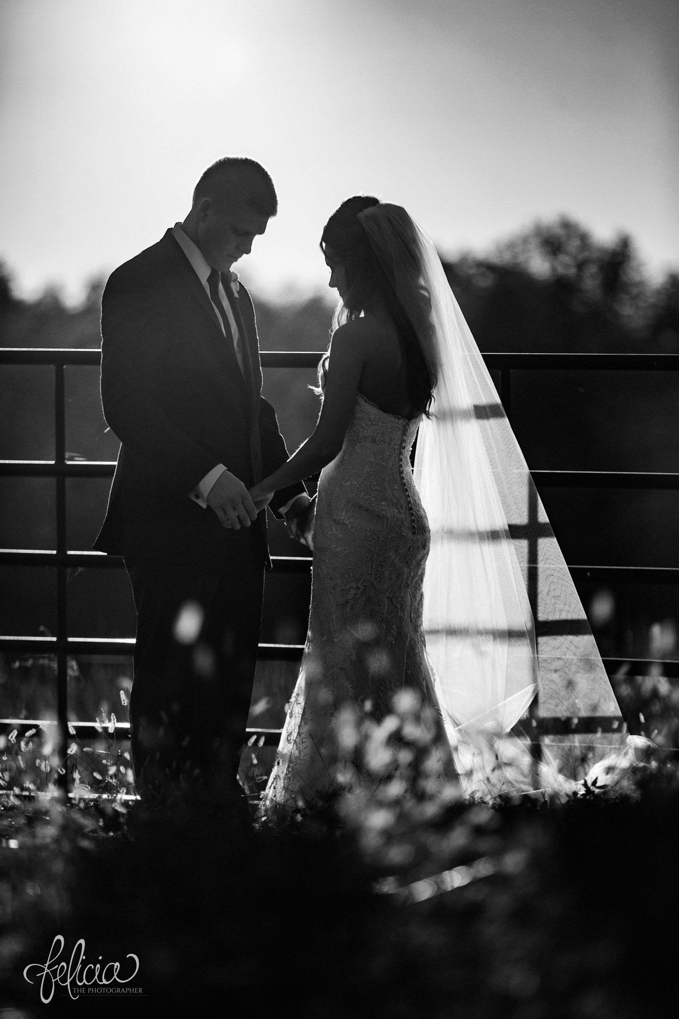 black and white | wedding | wedding photos | Rumely Event Space | wedding photography | images by feliciathephotographer.com | field background | nature | bride and groom portraits | sunlight | romantic sun | romance | sun flare | holding hands | fence | Maggie Sottero 