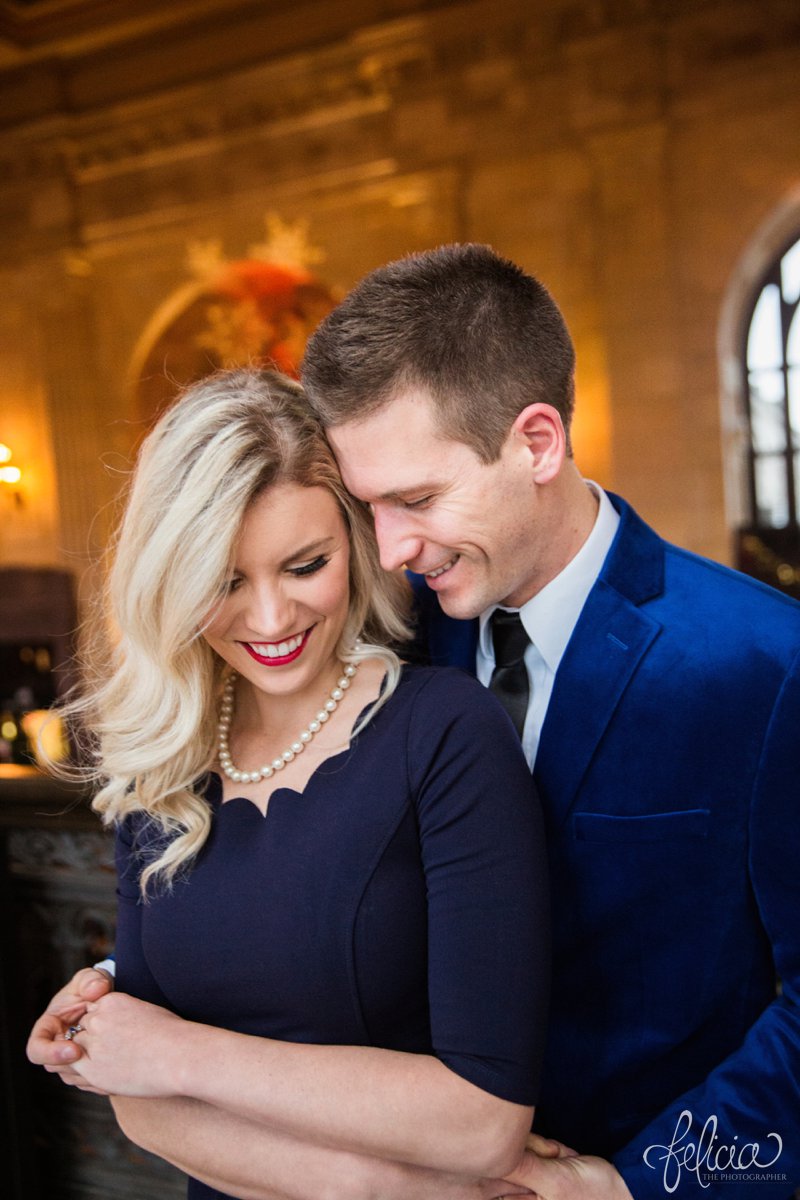 engagement photos | night engagement photos | Union Station | Kansas City | images by feliciathephotographer.com | romantic engagement | hugging pose | dramatic background | scallop neck dress | pearl accessories | blue blazer | holding hands 