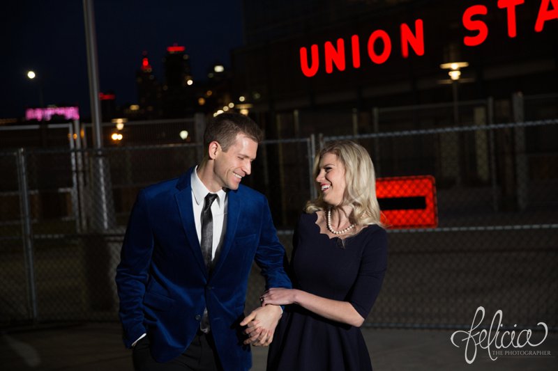 engagement photos | night engagement photos | Union Station | Kansas City | images by feliciathephotographer.com | romantic engagement | dramatic background | scallop neck dress | pearl accessories | blue blazer | Old Hollywood | holding hands | candid | laughing 