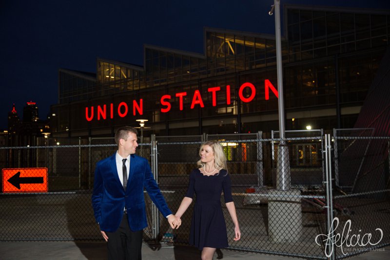 black and white | engagement photos | night engagement photos | Union Station | Kansas City | images by feliciathephotographer.com | romantic engagement | dramatic background | scallop neck dress | pearl accessories | blue blazer | chandelier | Old Hollywood | holding hands | candid | laughing 