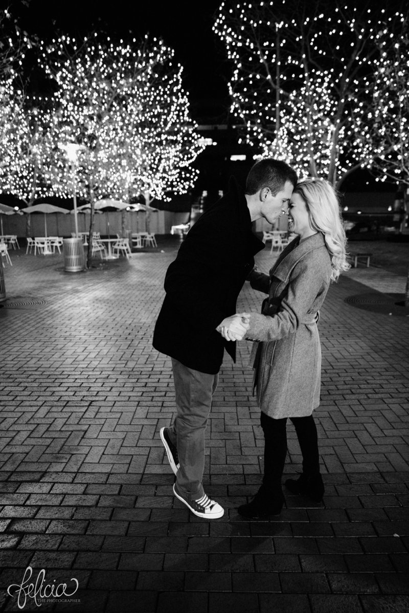 black and white | engagement photos | night engagement photos | Union Station | Kansas City | images by feliciathephotographer.com | romantic engagement | dramatic background | romantic poses | Old Hollywood | Christmas engagement photos | white lights | Christmas lights | dancing in the park | romantic pose | forehead touching | cobblestone