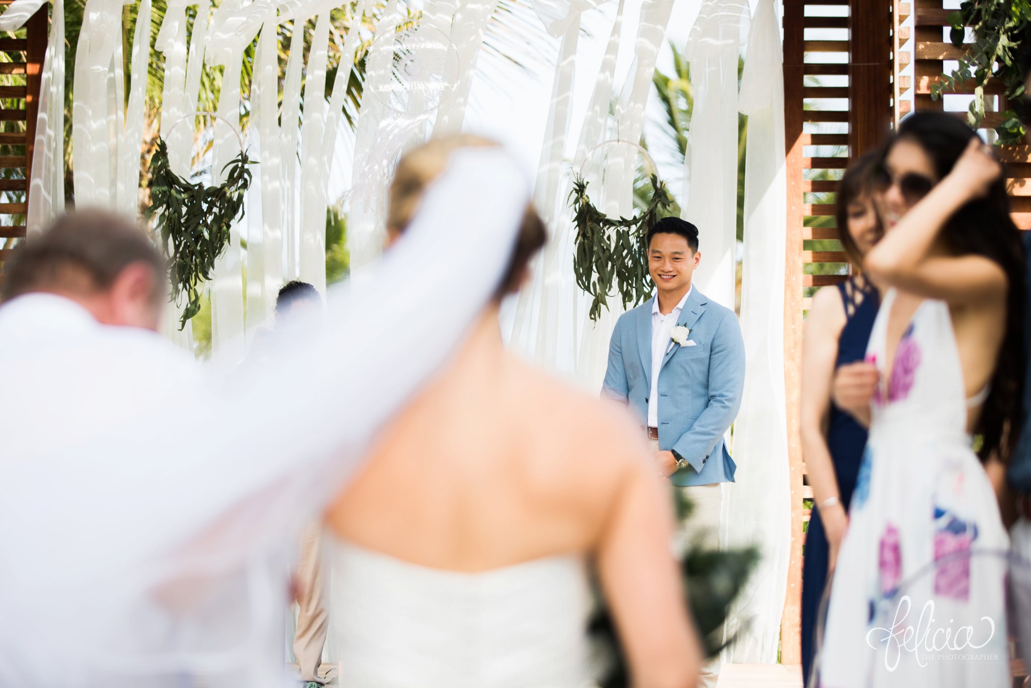 images by feliciathephotographer.com | Destination Beach Wedding | Unicco 20 87 | Photographer | L&S Travel | ceremony | walking down the isle | groom waiting for bride | white canopy | wood gazebo | palm trees | ocean view | blue jacket | veil 