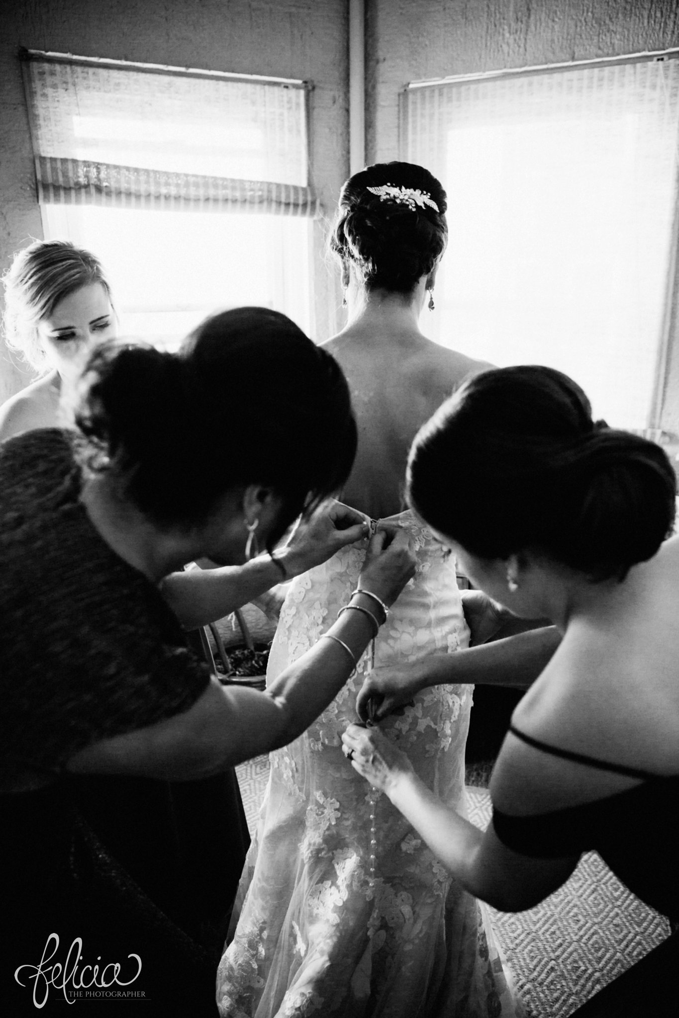 images by feliciathephotographer.com | wedding photographer | kansas city | getting ready | putting on the dress | bridesmaids | buttons | lace floral dress | strapless | emily hart | black and white | 