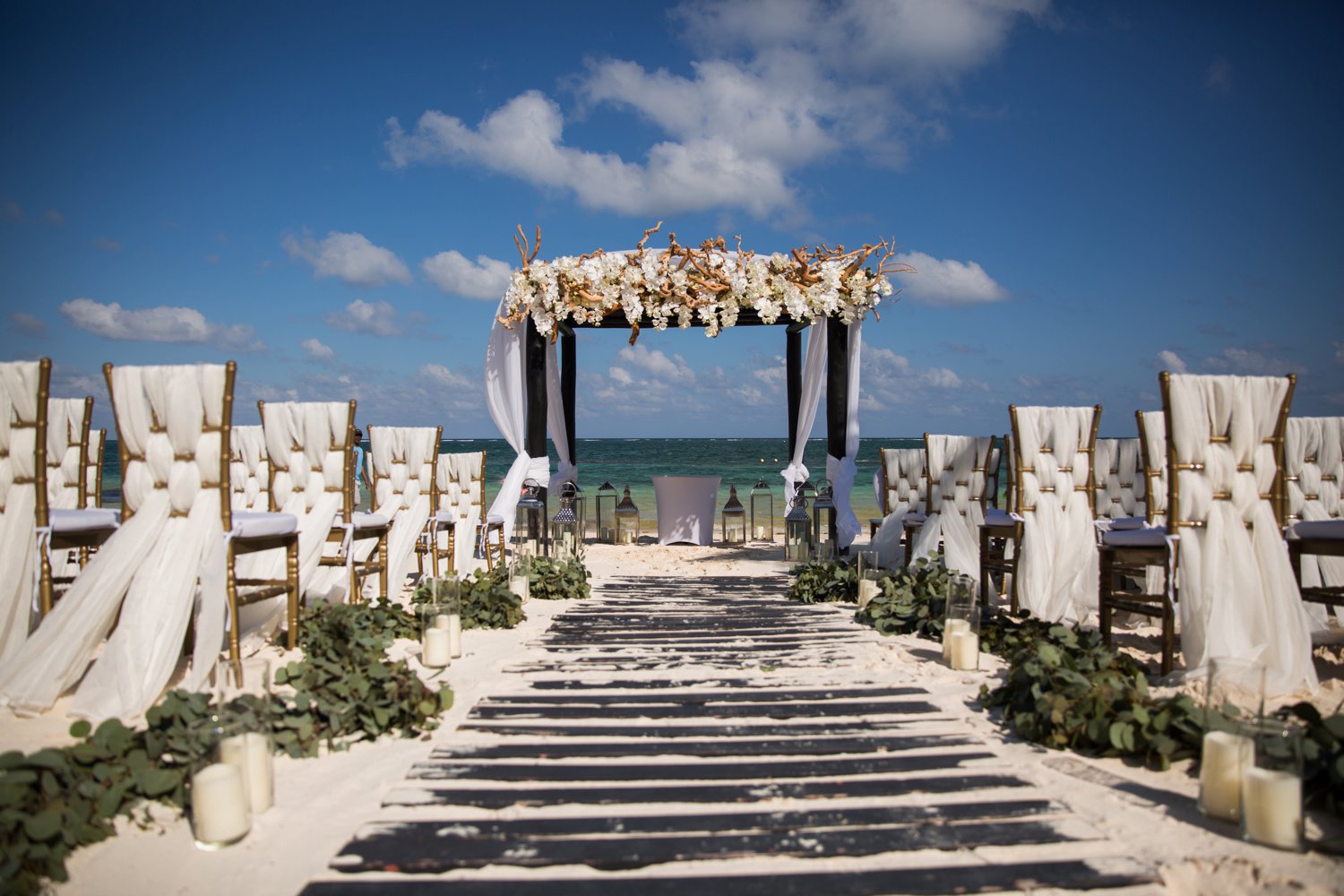  images by feliciathephotographer.com | destination wedding photographer | mexico | tropical | fiji | venue | azul beach resort | riviera maya | ceremony | white linen chairs | Beachwood aisle | candles | cabana | floral overhead | eucalyptus | 