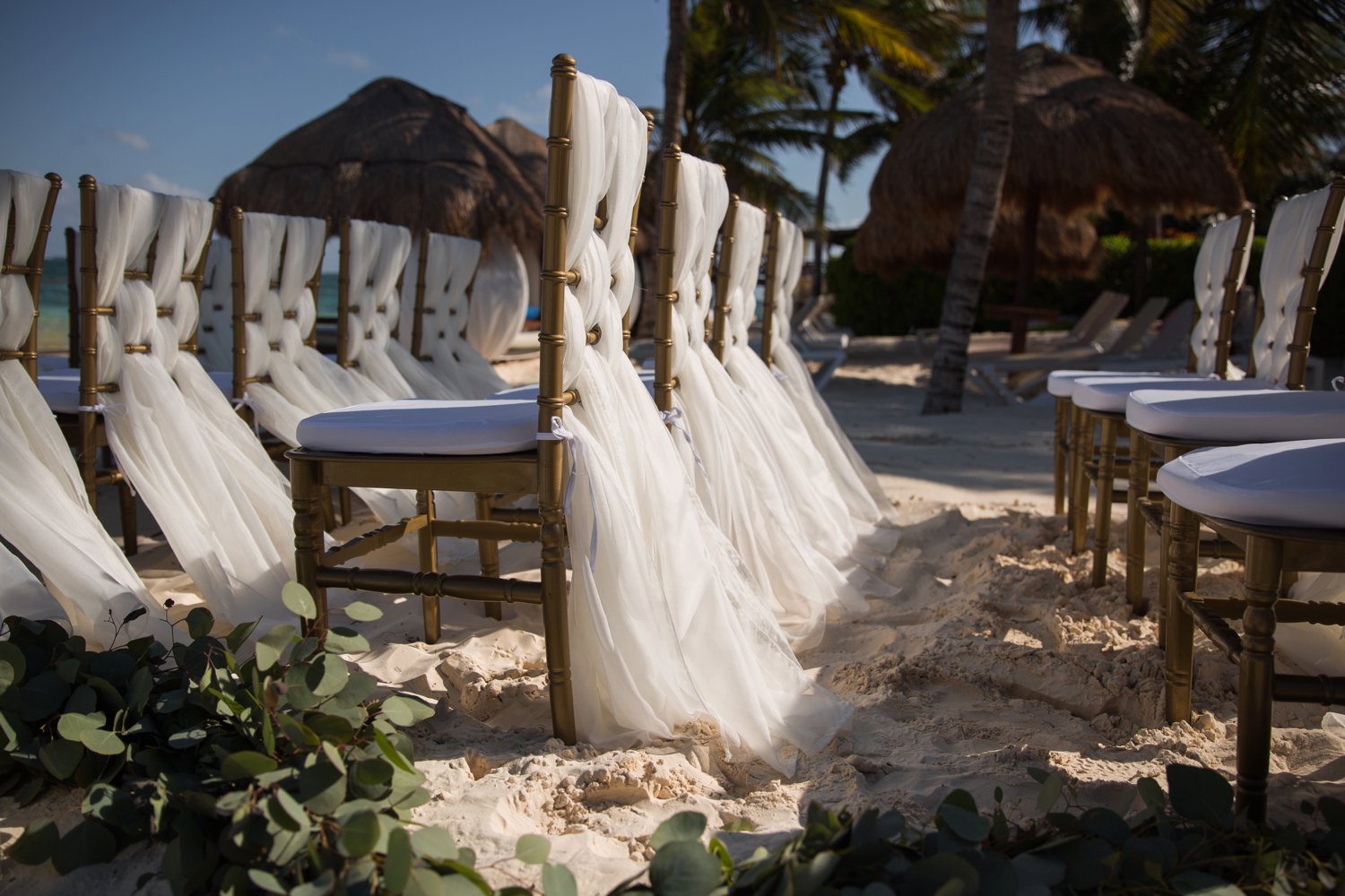 images by feliciathephotographer.com | destination wedding photographer | mexico | tropical | fiji | venue | azul beach resort | riviera maya | ceremony | white linen chairs | Beachwood aisle | candles | sand | eucalyptus |