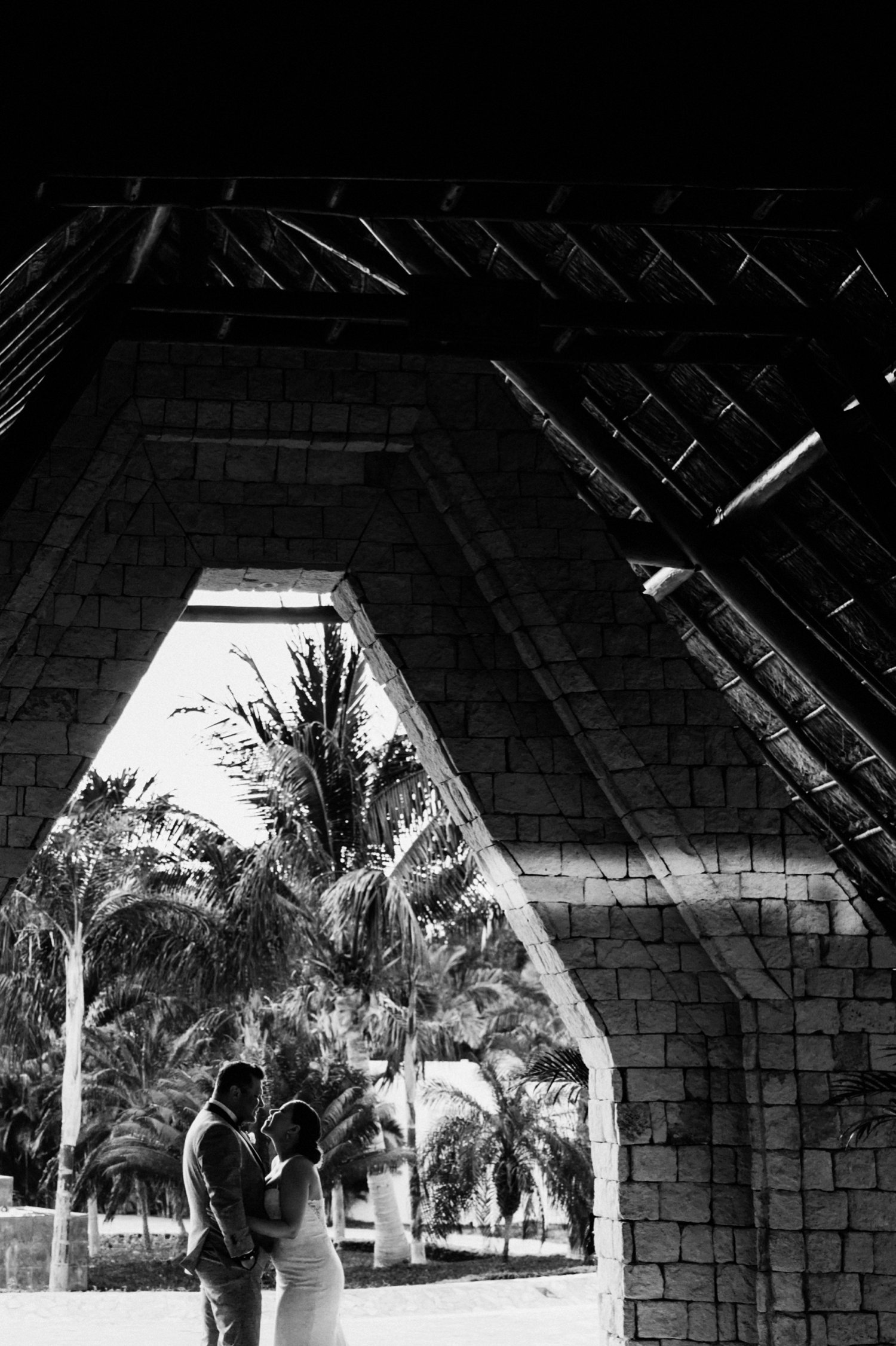  images by feliciathephotographer.com | destination wedding photographer | mexico | tropical | fiji | venue | azul beach resort | riviera maya | black and white bridal portraits | palm trees | contrast | stone building | grey suit | 