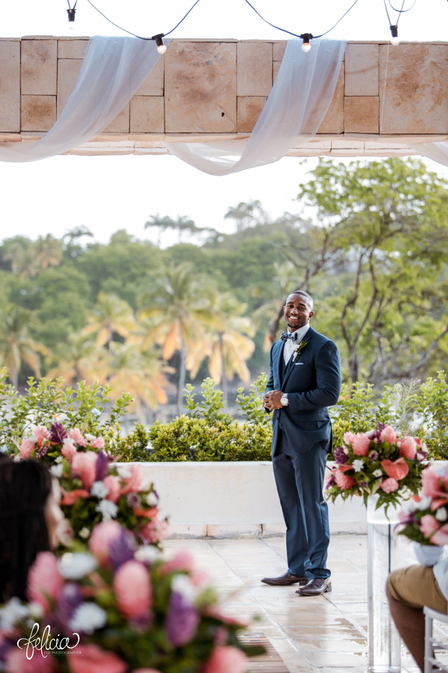   images by feliciathephotographer.com | destination wedding photographer | st lucia | l&s travel | the Royalton | ceremony | groom waiting at the end of the aisle | navy suit | paid bow tie | tropical | over look | 