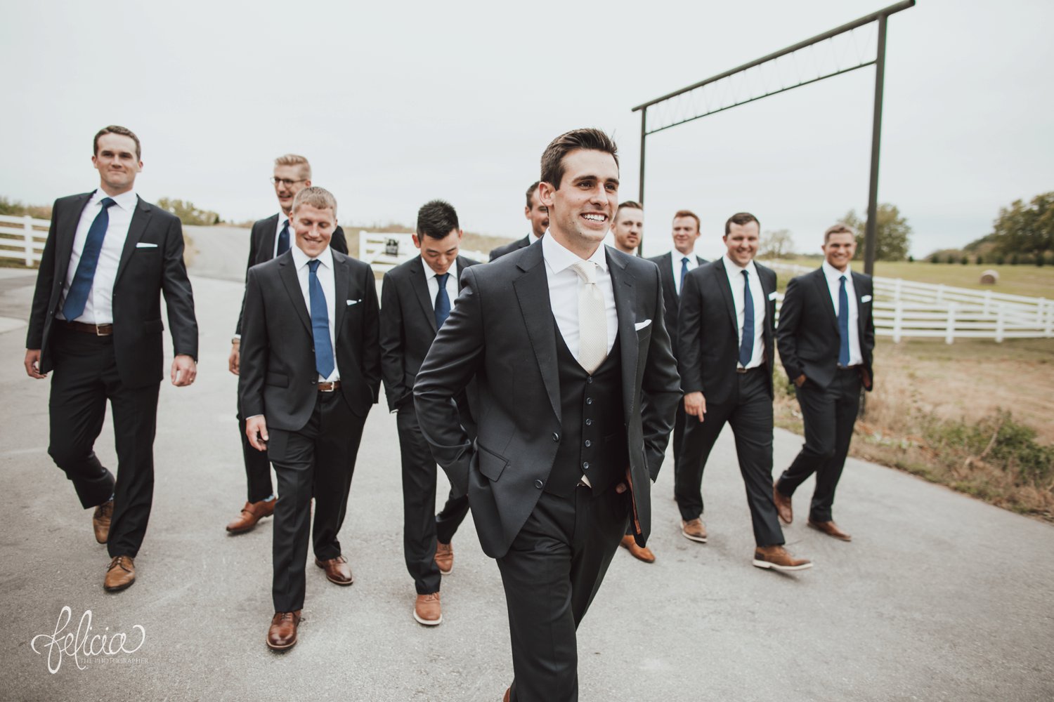 images by feliciathephotographer.com | destination wedding photographer | kansas city | eighteen ninety | classic | groomsmen portraits | walking | candid | cream tie | navy suit | royal blue | J. H. & sons clothier | brown leather shoes | country side | white picket fence | 