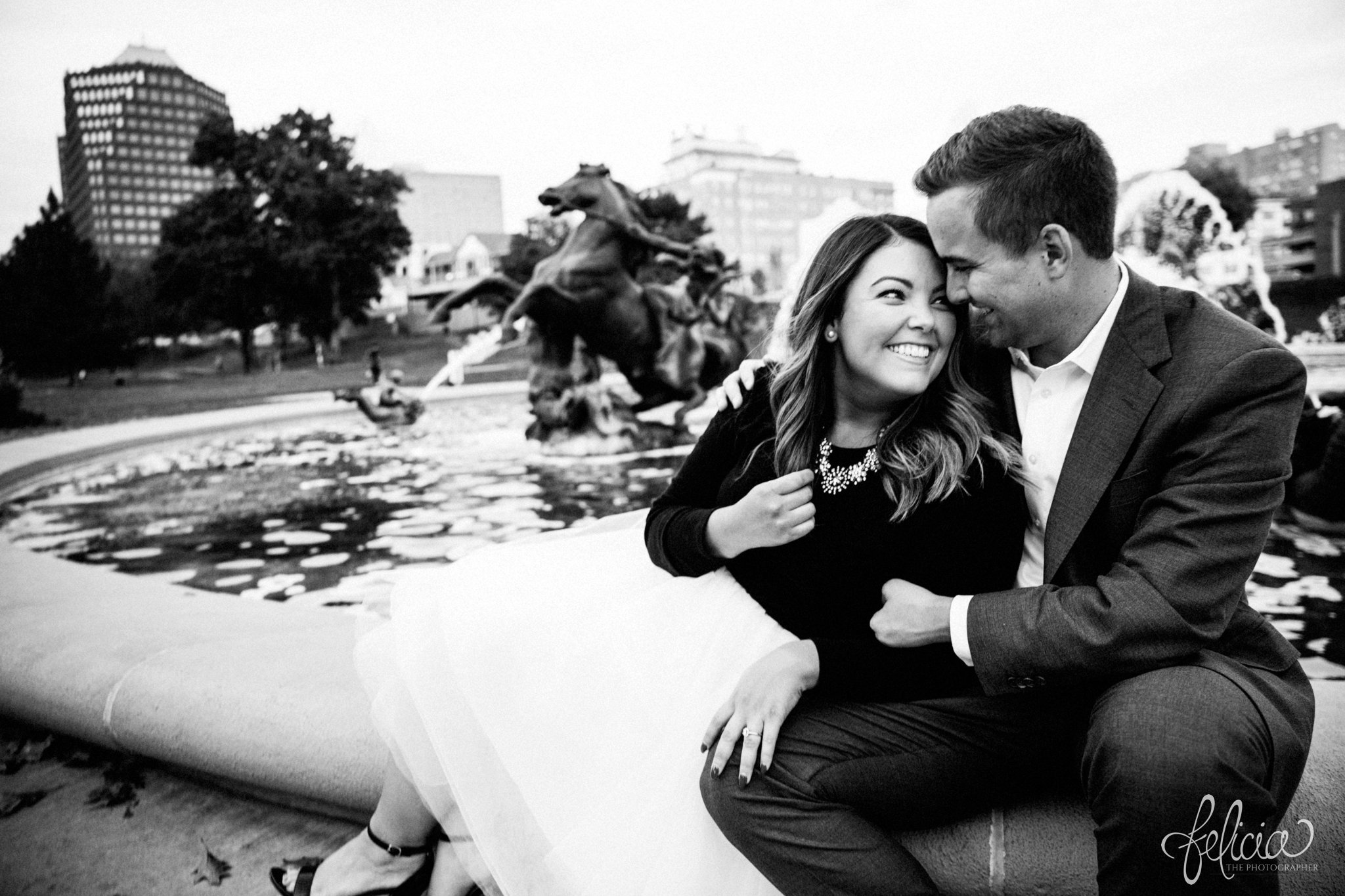 black and white | engagement photos | engagement photography | Kansas City | images by feliciathephotographer.com | architectural backgrounds | downtown | downtown Kansas City | fountain | white tulle | sitting | cuddling | laughter | Plaza Country Club 