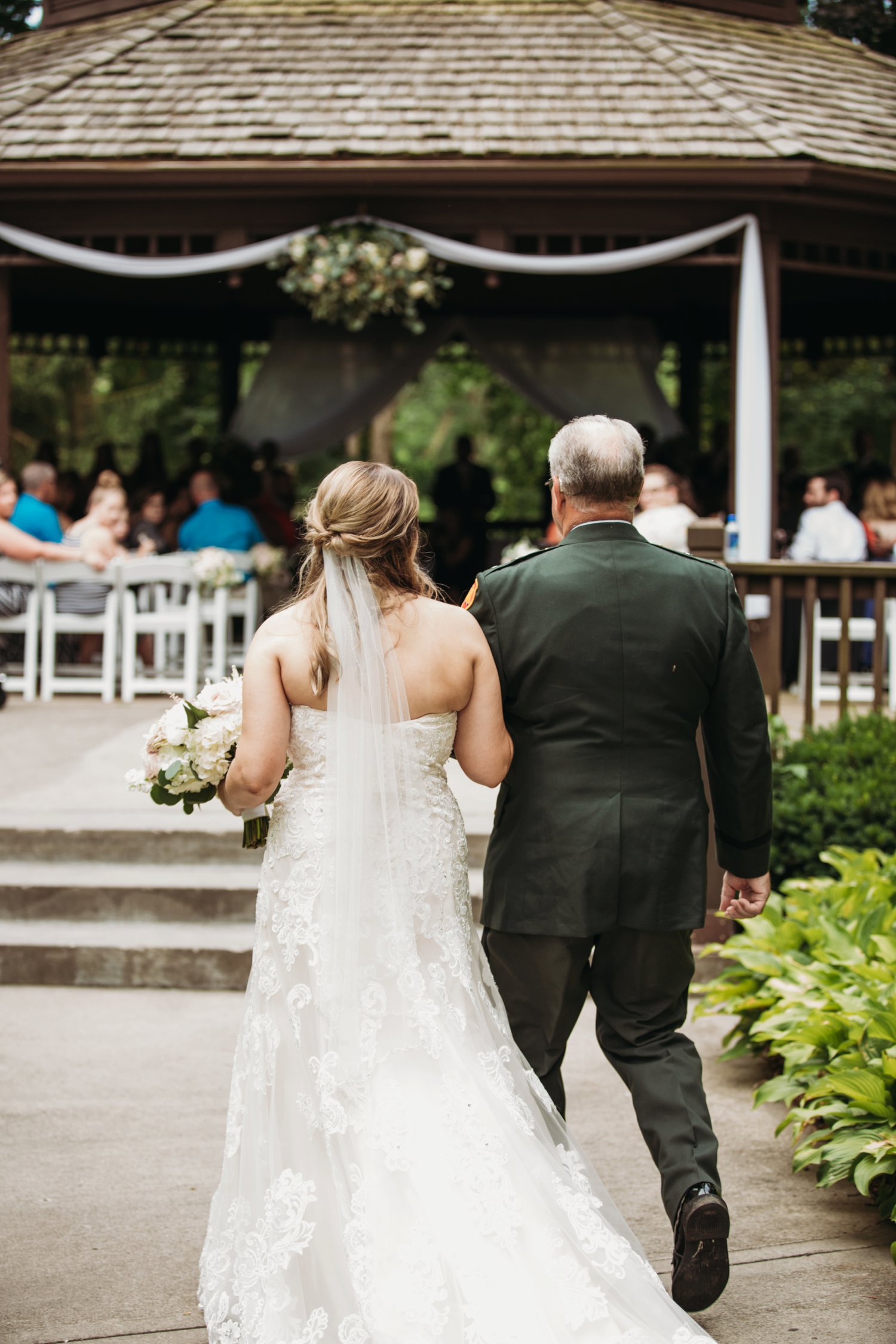  images by feliciathephotographer.com | destination wedding photographer | kansas city | summertime | elms spa | classy | ceremony | gazebo | white tule | walking down the aisle | lace gown | long veil | dress gallery wichita | 